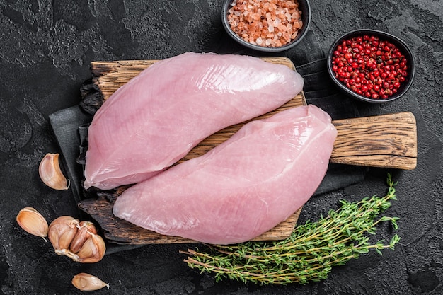 Uncooked Raw Turkey Breasts fillet steaks with herbs Black background Top view