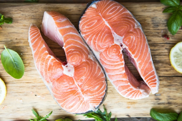 Uncooked salmon fillet steak with lemon sea salt and herb on wooden board. 