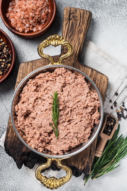 Uncooked vegan mince meat raw plant based meat with thyme in skillet White background Top view