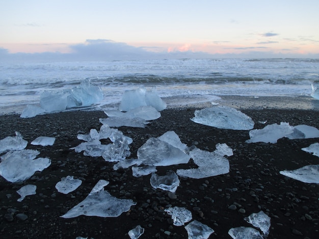 Uncountable icebergs on the black sand beach against sunset sky, South Iceland