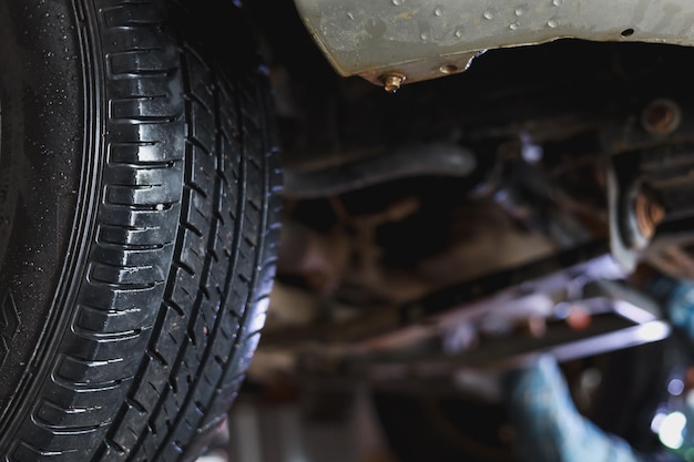 The undercarriage of a car with a jack is lifted for repairs.