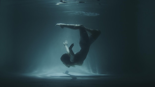 Underwater gymnastics of a beautiful girl in a white dress