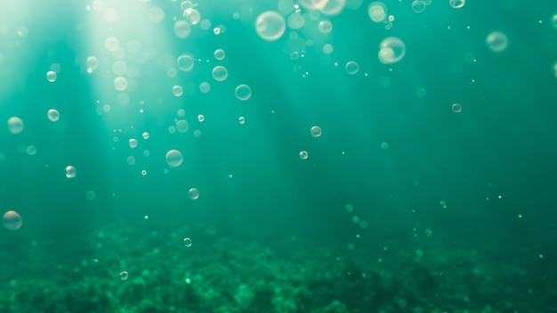 Underwater view of water surface and floor with bubbles Green ocean background