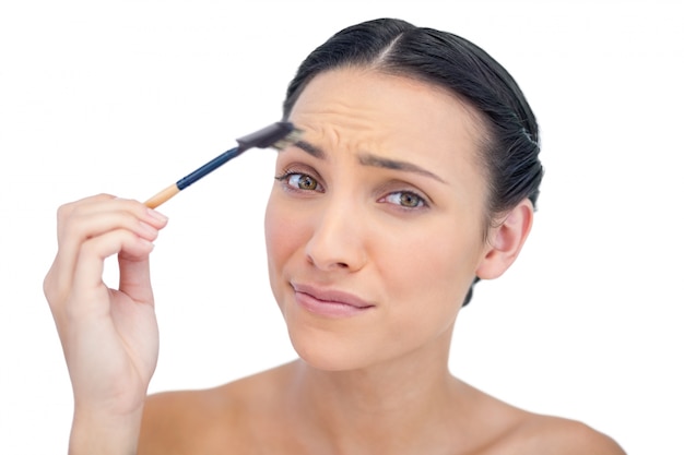 Uneasy young model using eyebrow brush