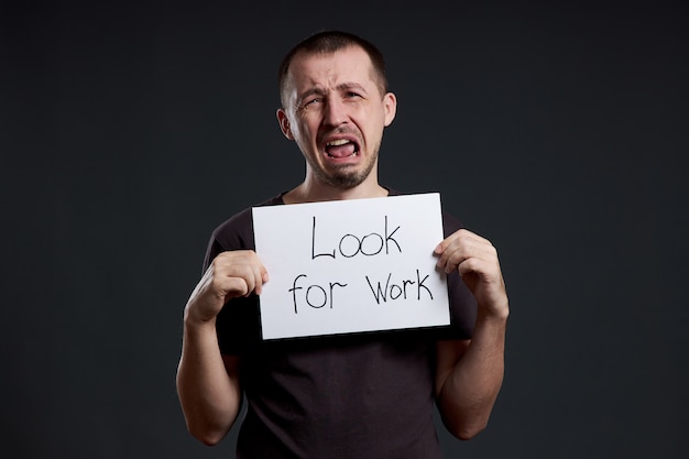 Unemployment and crisis. Man holds a sign with the words looking for work