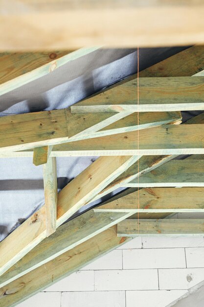 Unfinished attic wooden roof framing with vapor barrier close up View on timber rafters and beams