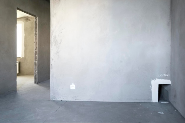 Unfinished building. Rough finish of the apartment. A large empty room with plastered concrete walls. Interior renovation.