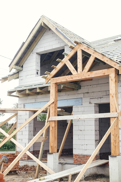 Unfinished house Wooden roof framing with vapor barrier and dormer on block walls with windows New modern farmhouse construction Timber trusses Rafters and beams on aerated concrete blocks