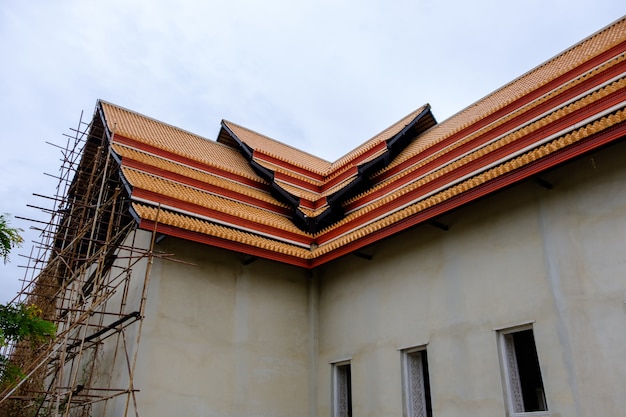 The unfinished traditional Thai church with the wooden scaffolding beside the cement wall