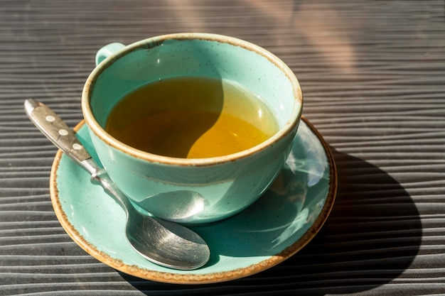 Unfinished turquoise cup of tea on a table in a cafe in the sunlight