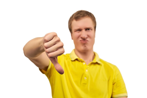 Unhappy annoyed man in yellow Tshirt showing thumbs down gesture isolated on white background