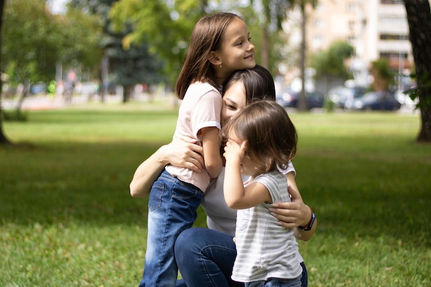 Unhappy little girl feeling jealous while mother spending time with her baby brother at street