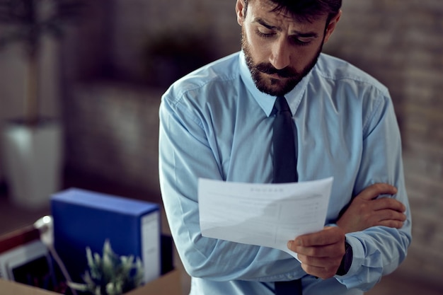 Unhappy male entrepreneur reading a report after being fired at work