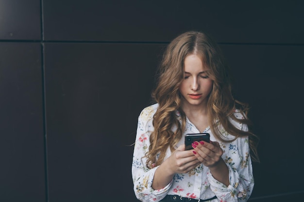 Unhappy teen girl looks at her smartphone experiencing anxiety and sad