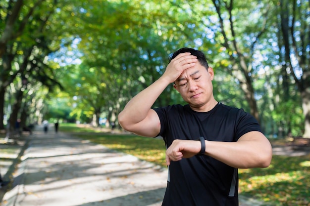 Unhappy and upset male athlete looking at fitness with smartwatch bad workout result asian man