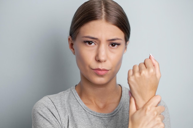 Unhappy woman suffering from pain in hand at home