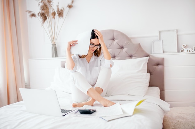 Unhappy young girl received notice of bank debt or eviction, feeling bad lying on bed, bad news, headache