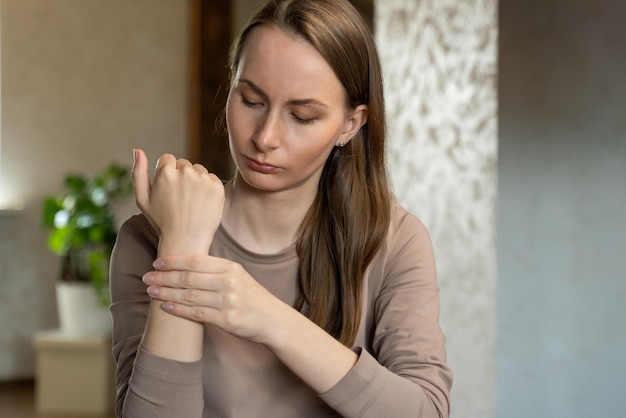 An unhappy young woman suffering from wrist pain at home