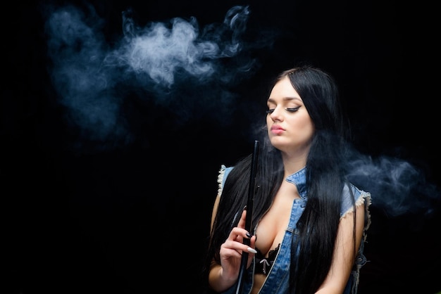 Unhealthy addiction Tabacco drug Bad habit Woman vapor sexy woman smoking cigar exhale smoke on black background hookah bar Electronic cigarette copy space relax in hookah bar