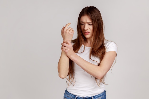 Unhealthy woman standing with grimace of pain massaging sore wrist suffering hand injury or sprain