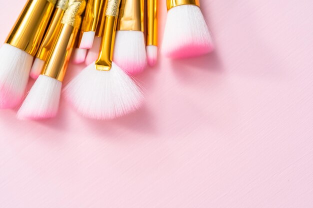 Unicorn color makeup brushes on a pink background.