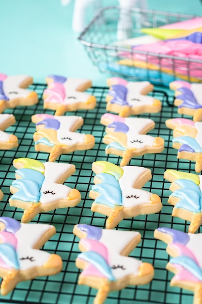 Unicorn sugar cookies decorated with royal icing and food glitter on a blue background.