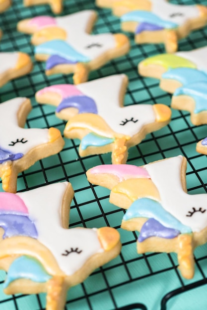 Unicorn sugar cookies decorated with royal icing and food glitter on a blue background.