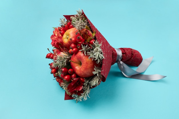 Photo unique gift in the form of a red bouquet of flowers and fruits on a blue background