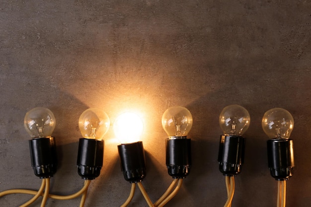 Unique glowing light bulb among switched off ones Individuality and leadership concept