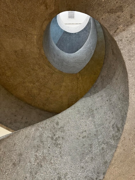 Unique spiral staircase with raw exposed concrete or cement screed finishes on the curved wall