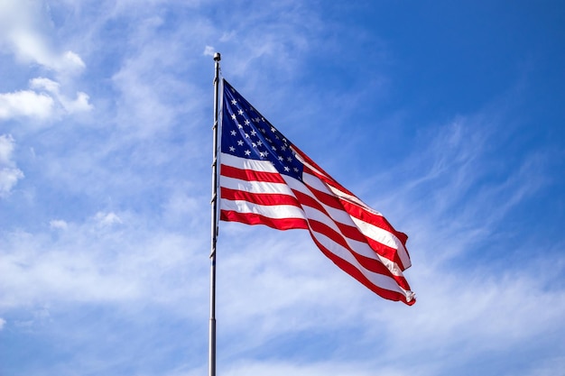 United States flag on a pole waving on blue sky background