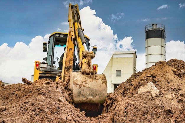 A universal excavator is working on a construction site against a cloudy sky Earthworks at a construction site Modern earthmoving equipment The contractor is doing construction work