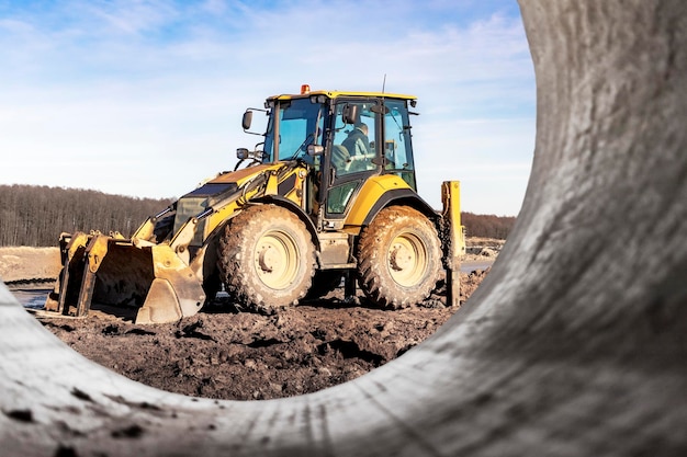 A universal excavator or loader is working on a construction site against a cloudy sky Earthworks at a construction site Modern earthmoving equipment The contractor is doing construction work