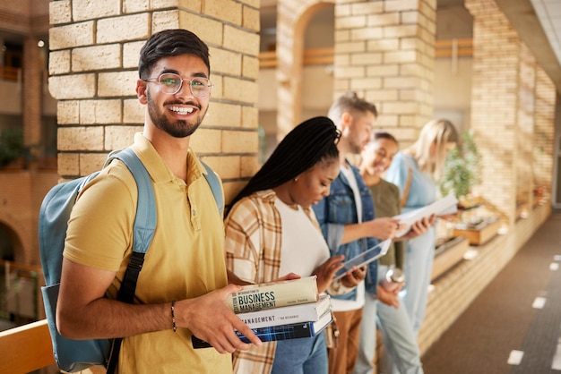 University hallway and portrait of Indian man and students standing in row together with books at business school Friends education and future happy man in study group on campus in lobby for exam