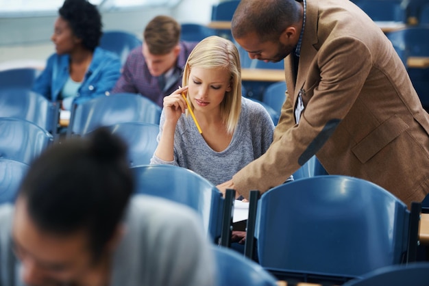 University helping and professor with student in classroom studying for test exam or assignment Education learning and teacher talking and explaining college information to woman in lecture hall