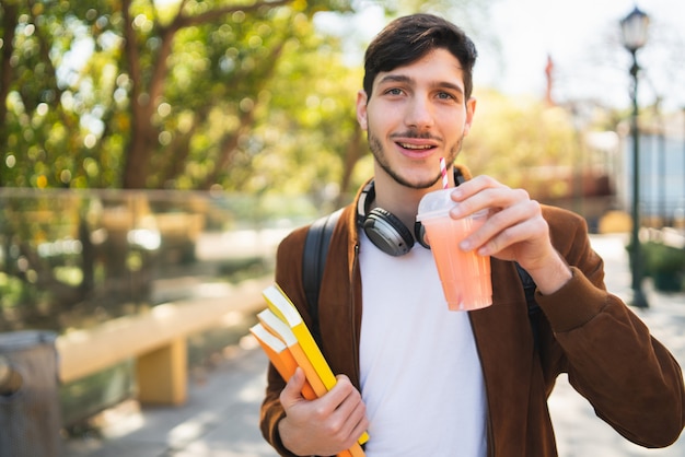 University student walking on the street while holding his books