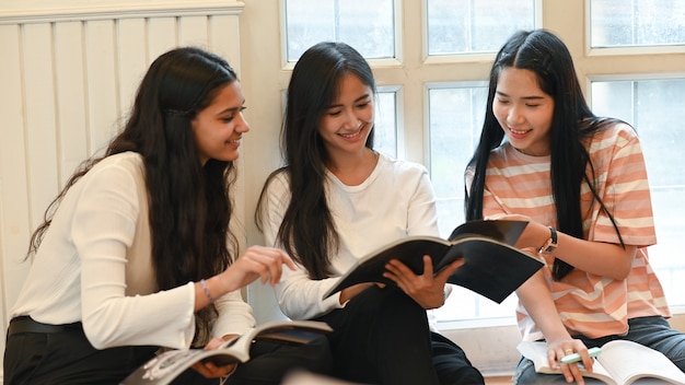 University students are talking and reading a magazine while sitting together in the living room