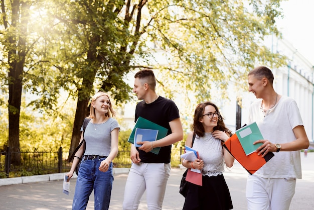 University students walking to the hall of residence after lectures and seminars, sharing ideas and having conversation about classes. Students walking in the park in the evening