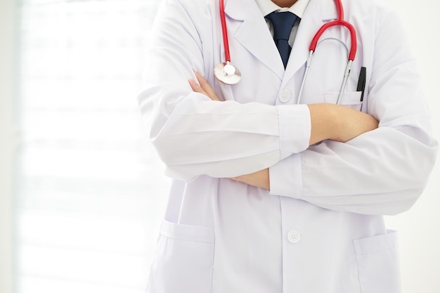 Unknow doctor posing with arms crossed in the office he is wearing a stethoscope