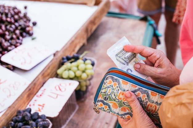 Unknowing senior woman taking a 5 euro bill out of her wallet to pay