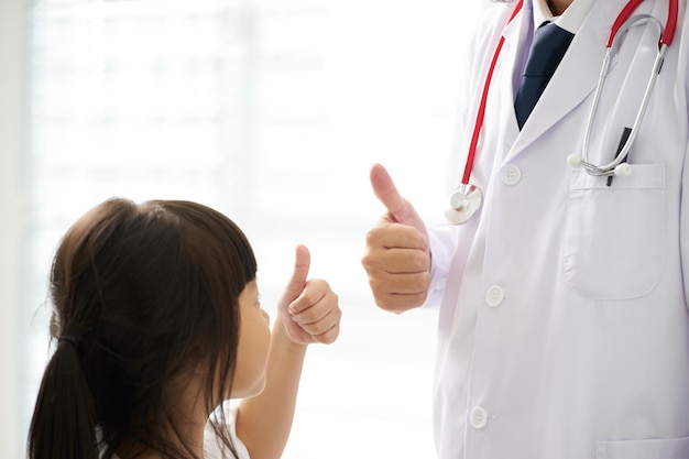 Unknown doctor and little girl hands with thumbs up