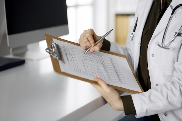 Unknown female doctor using clipboard in clinic. Perfect medical service in hospital. Medicine concept.