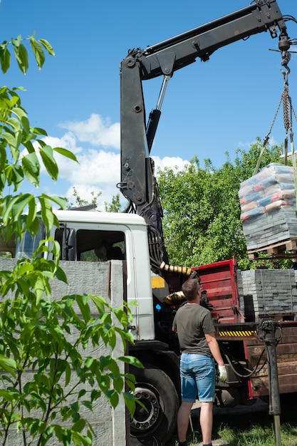 Unloading paving slabs from a truck Men unload paving slabs using a manipulator Workers unload building materials from a large machine