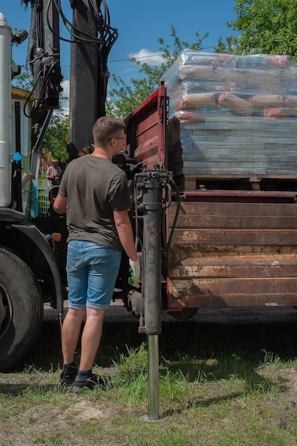 Unloading paving slabs from a truck Men unload paving slabs using a manipulator Workers unload building materials from a large machine