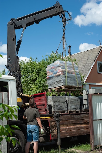 Unloading paving slabs from a truck Men unload paving slabs using a manipulator Workers unload building materials from a large machine