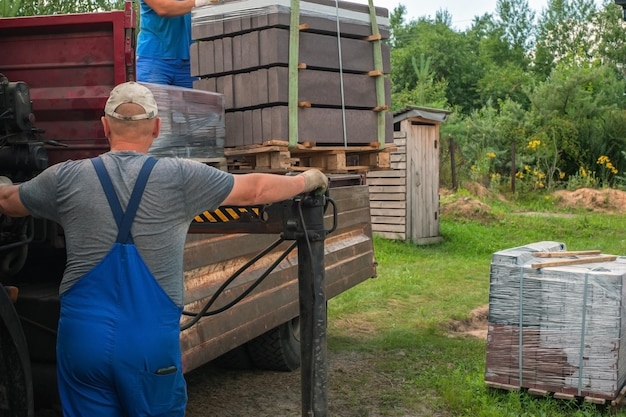 Unloading paving slabs from a truck Men unload paving slabs using a manipulator Workers unload building materials from a large machine