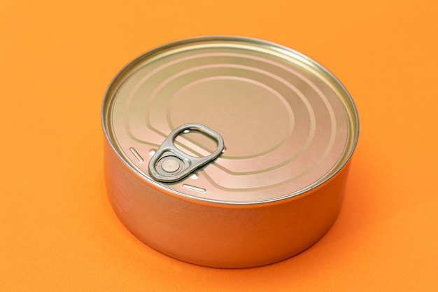 Unopened tin can with blank edge on orange background