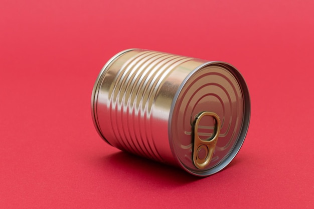 Unopened tin can with blank edge on red background