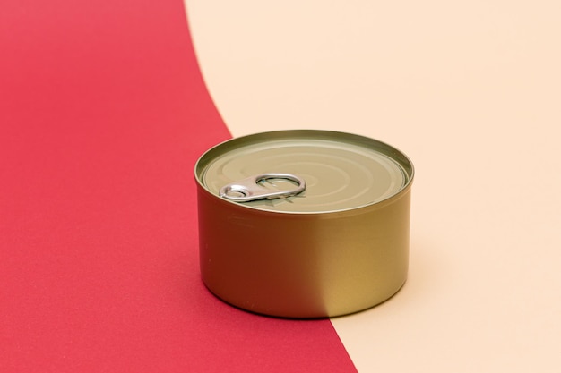 Unopened tin can with blank edge on split red and beige background