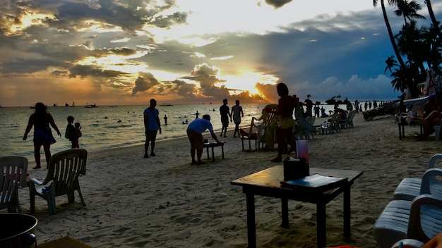 Unrecognisable people standing at the beach while watching the sunset